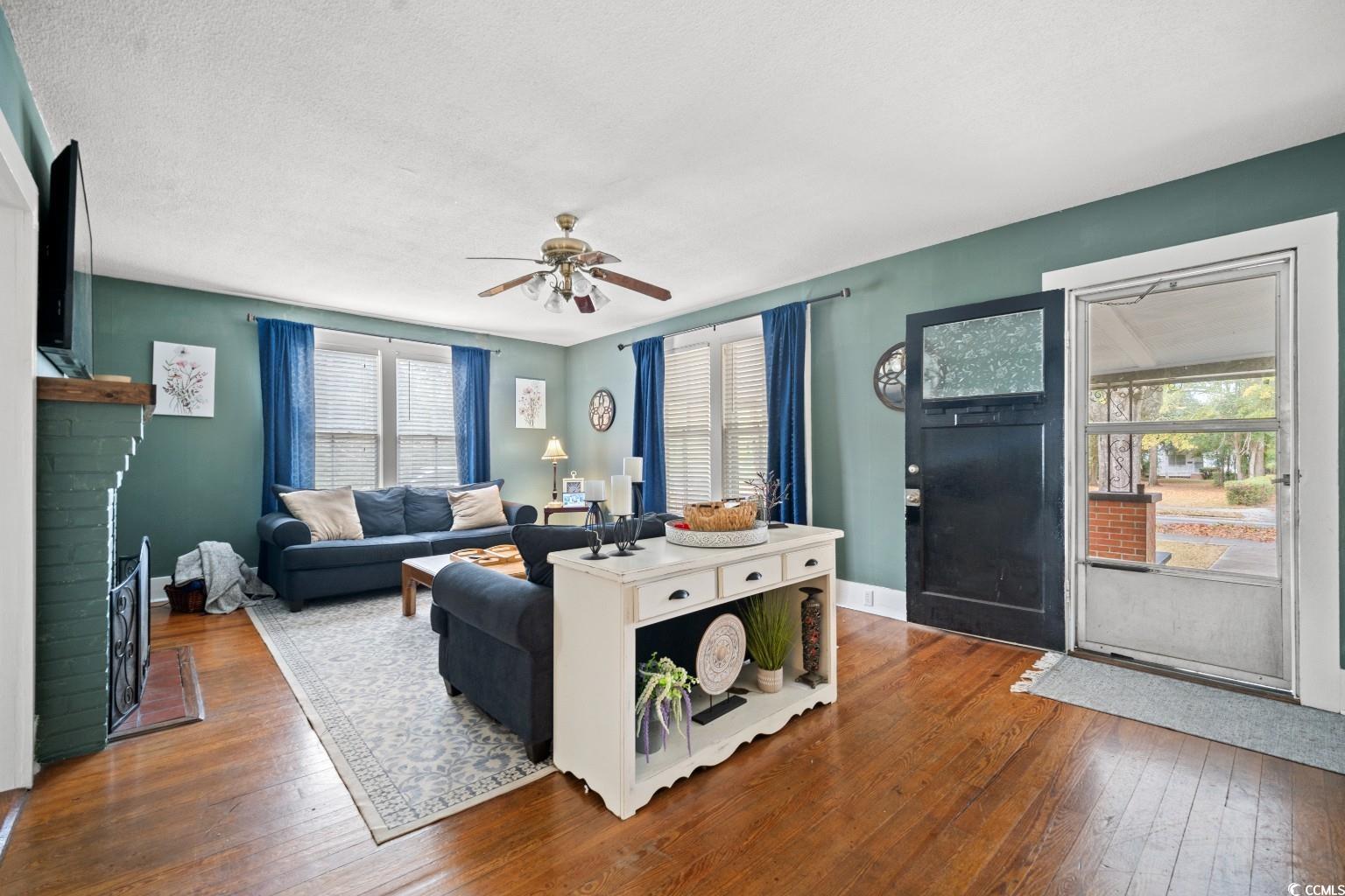 222 East Wine Street Mullins, SC 29574 - Photo 10 of 40 Living room with a fireplace, hardwood / wood-style floors, ceiling fan, and a textured ceiling