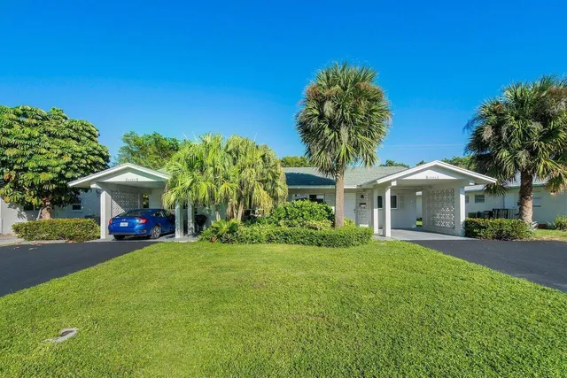 a front view of a house with a garden and trees
