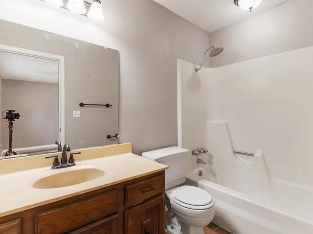 a bathroom with a granite countertop toilet a sink and a mirror