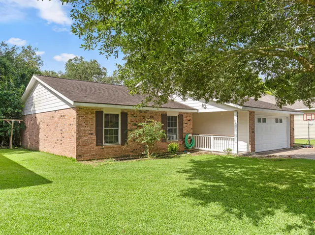 a view of a house with a yard and a large tree