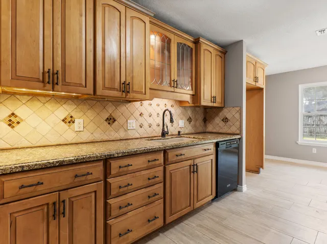 a kitchen with granite countertop wooden cabinets and sink
