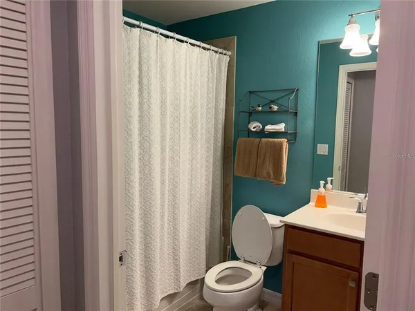 a bathroom with a toilet a sink and shower curtain