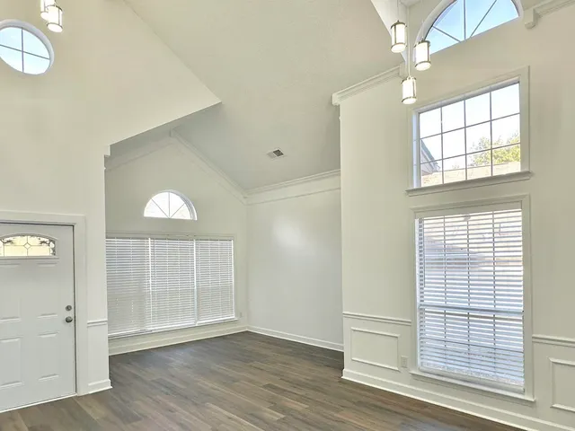 an empty room with wooden floor cabinet and windows