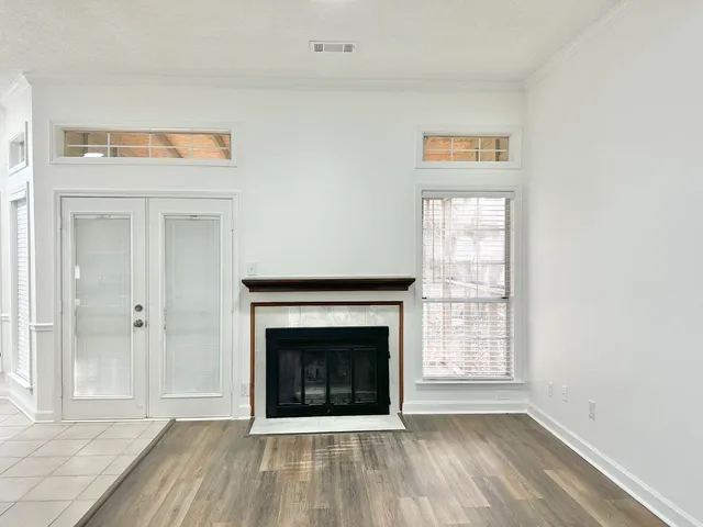 a view of an empty room with wooden floor a fireplace and a window