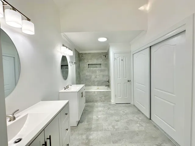 a bathroom with a double vanity sink toilet mirror and bathtub