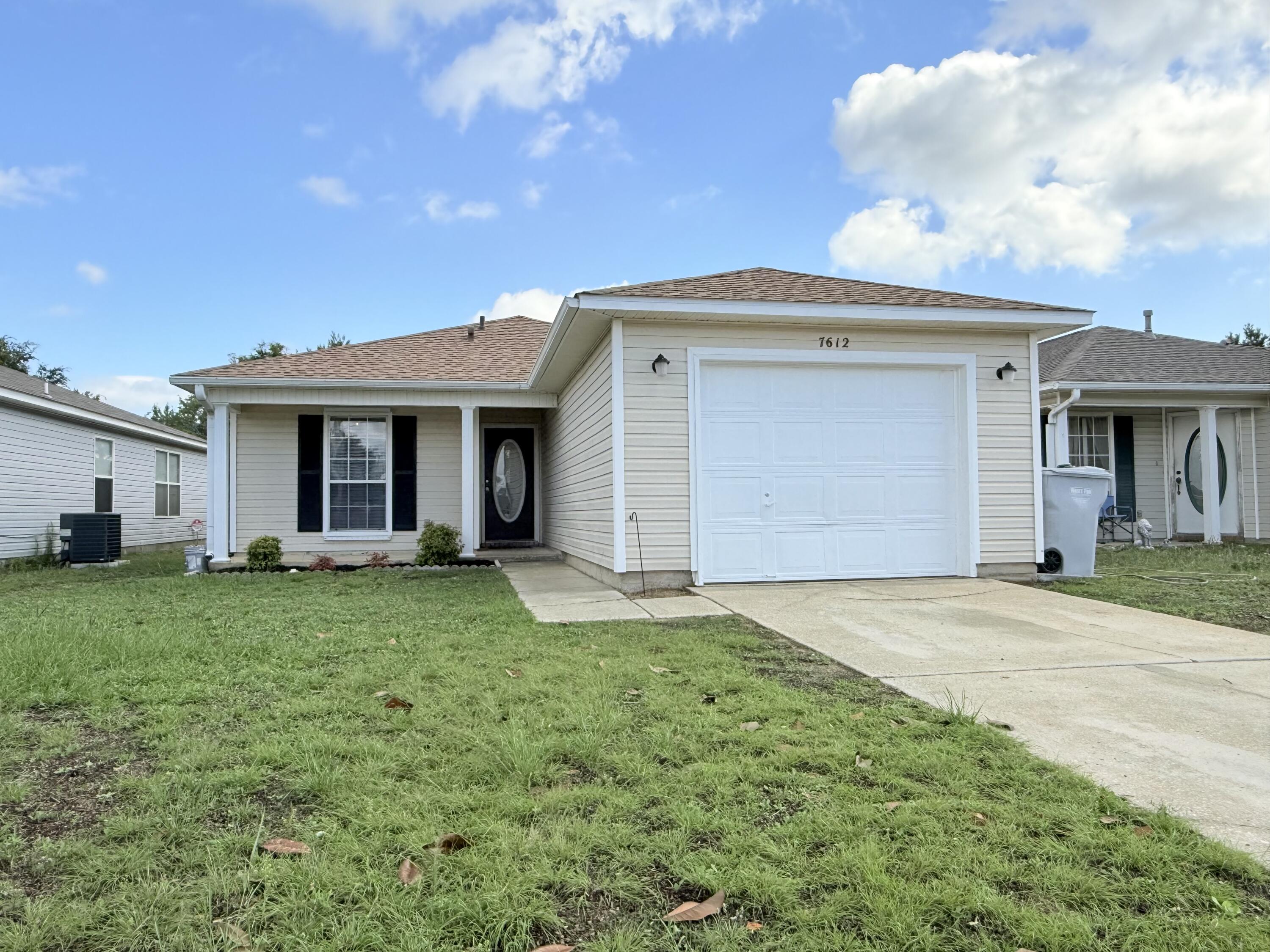 7612 Chablis Circle Navarre, FL 32566 - Photo 1 of 16 a front view of a house with a garden and yard