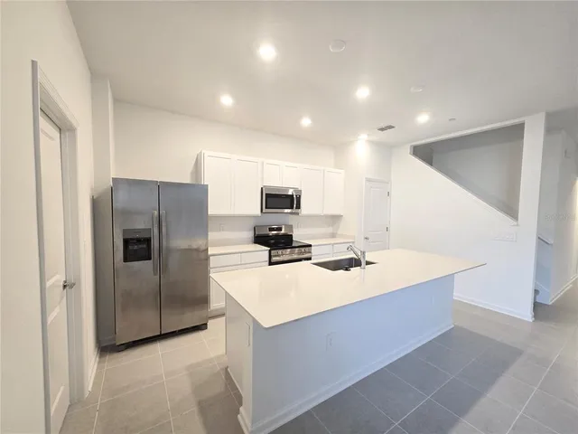 a kitchen with stainless steel appliances a refrigerator sink and microwave