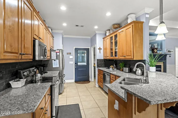 a kitchen with stainless steel appliances granite countertop a sink a stove and a wooden cabinets