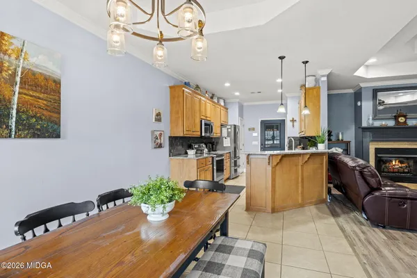 a kitchen with stainless steel appliances kitchen island granite countertop a refrigerator a oven a sink and a dining table with wooden floor
