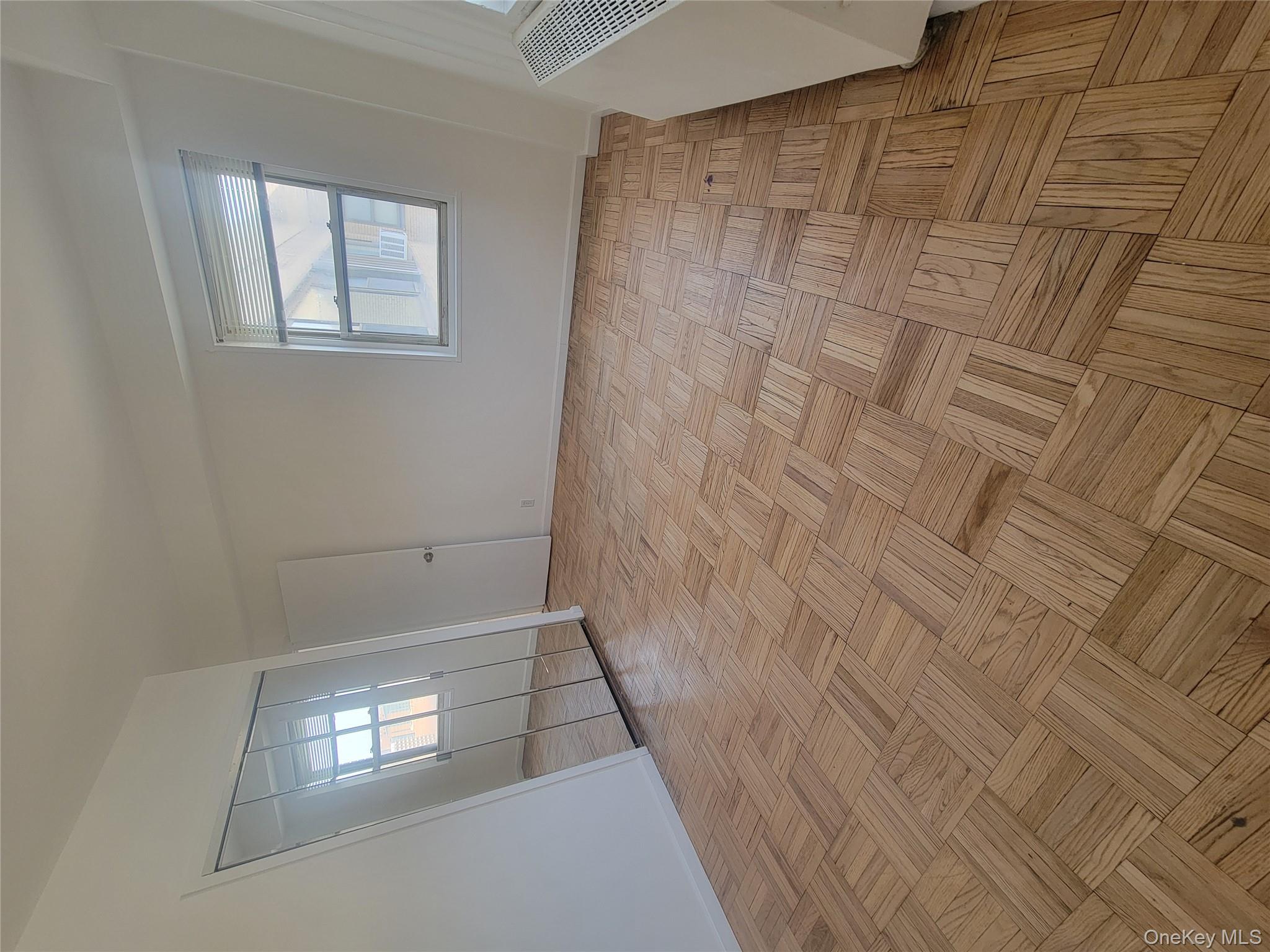 7 Fordham Hill Ovl, Unit 16C Bronx, NY 10468 - Photo 11 of 17 an empty room with wooden floor and windows