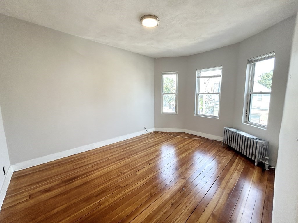 18 Eastman Street, Unit 2 Boston, MA 02125 - Photo 3 of 9 an empty room with wooden floor and windows