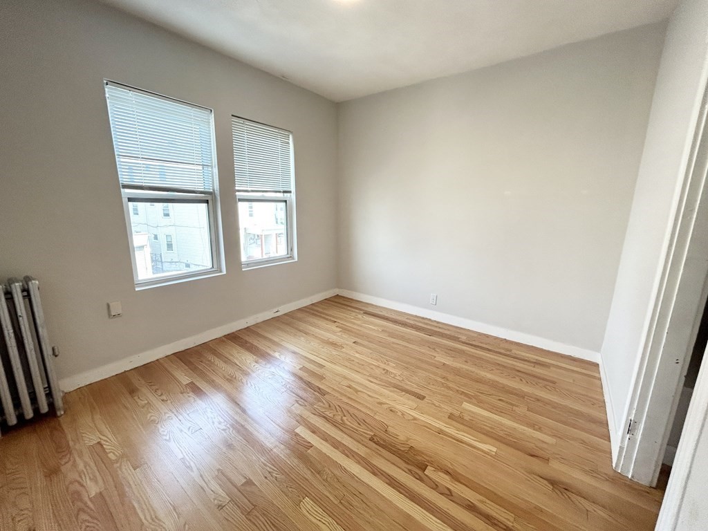 18 Eastman Street, Unit 2 Boston, MA 02125 - Photo 4 of 9 a view of an empty room with wooden floor and a window