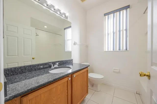 a bathroom with a granite countertop sink a toilet a mirror and a window