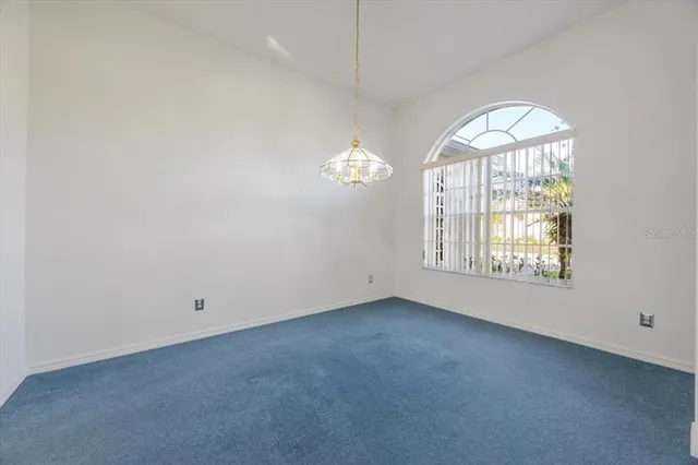 an empty room with chandelier fan and windows