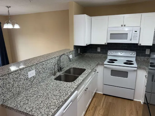 a kitchen with granite countertop a sink a stove and cabinets