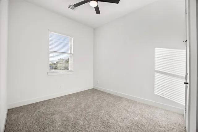 an empty room with a window and a ceiling fan
