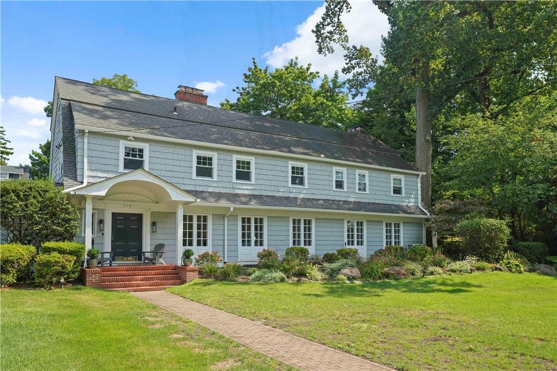 a front view of a house with garden and trees