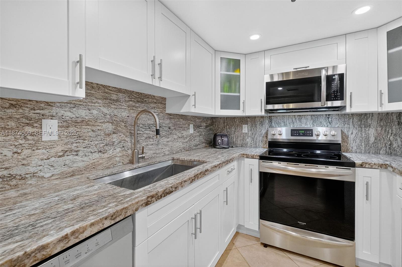 2401 Collins Avenue, Unit 1005 Miami Beach, FL 33140 - Photo 7 of 19 a kitchen with granite countertop a sink stainless steel appliances and cabinets