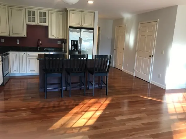 a kitchen with stainless steel appliances a dining table chairs and a refrigerator