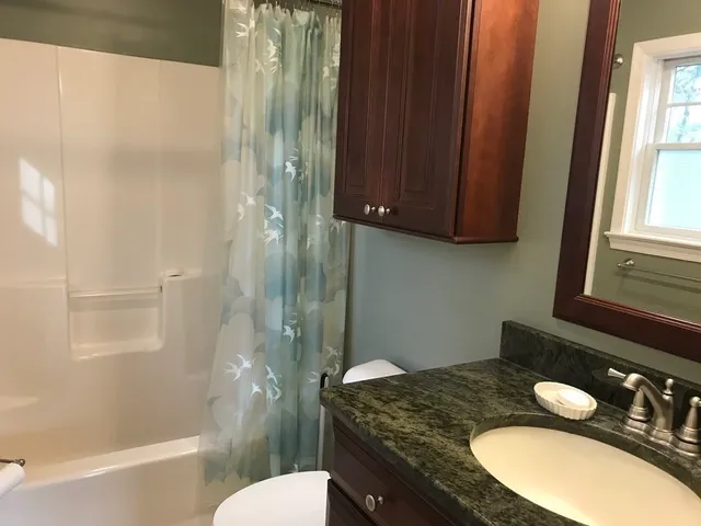 a bathroom with a granite countertop sink toilet a mirror and shower