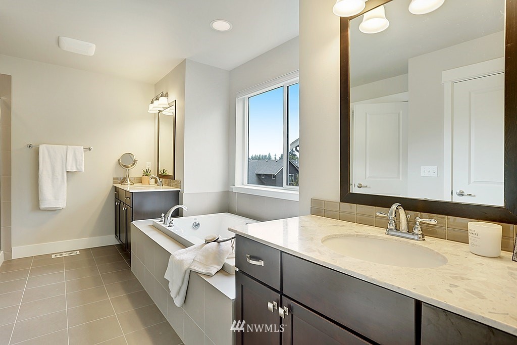 5213 Northeast 2nd Place Renton, WA 98059 - Photo 18 of 25 a bathroom with a double vanity sink a mirror and a bathtub