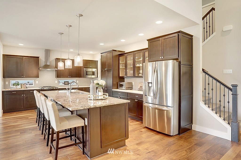 5213 Northeast 2nd Place Renton, WA 98059 - Photo 8 of 25 a kitchen with stainless steel appliances a refrigerator a stove a sink a dining table and chairs