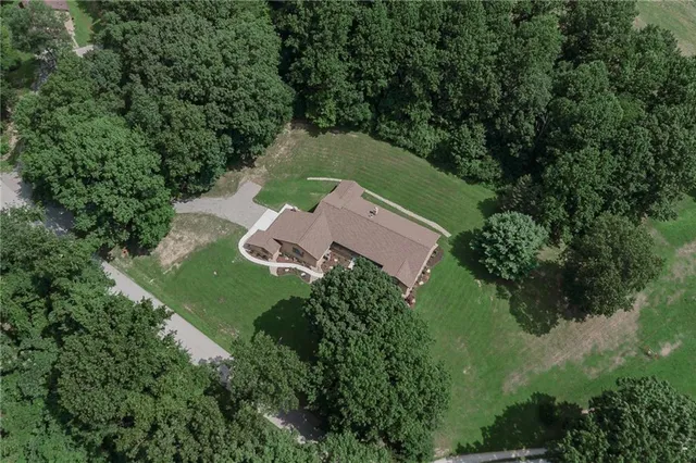 an aerial view of a house with outdoor space and trees all around