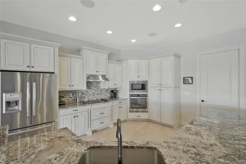 a kitchen with stainless steel appliances granite countertop a refrigerator and a stove top oven