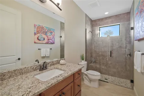 a bathroom with a granite countertop toilet a sink and shower