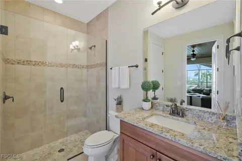 a bathroom with a granite countertop sink a toilet and shower