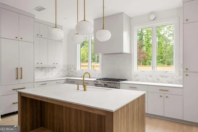 a kitchen with a sink dishwasher a large window with white cabinets and wooden floor