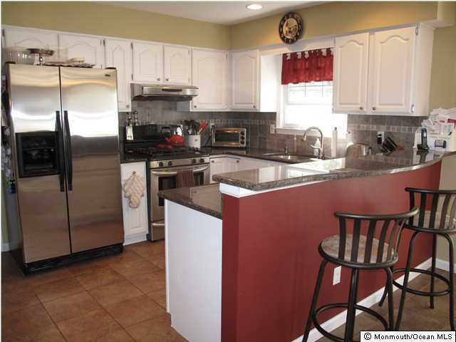 45 Sweet Gum Road Howell, NJ 07731 - Photo 12 of 25 a kitchen with stainless steel appliances granite countertop a stove a refrigerator a sink a dining table and chairs