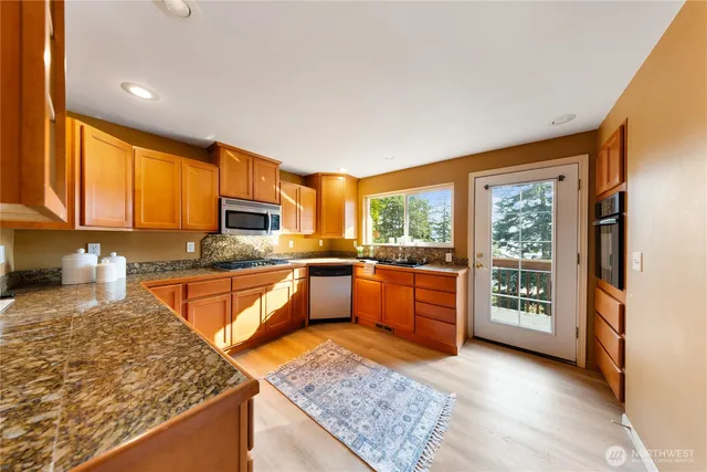 a kitchen with stainless steel appliances granite countertop sink stove and large window