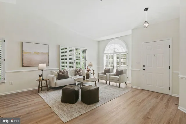 a living room with furniture large window and wooden floor