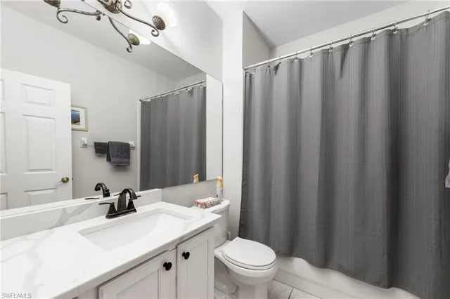 a bathroom with a sink a toilet a mirror and shower curtain