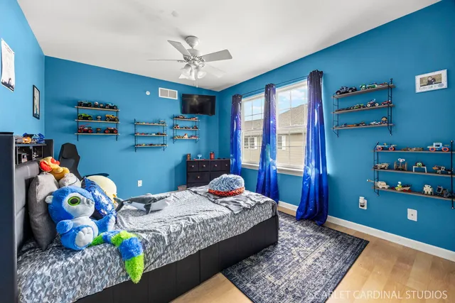 a bedroom with a bed a dresser and a chandelier