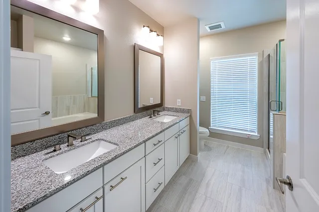 a bathroom with a granite countertop double vanity sink and a mirror