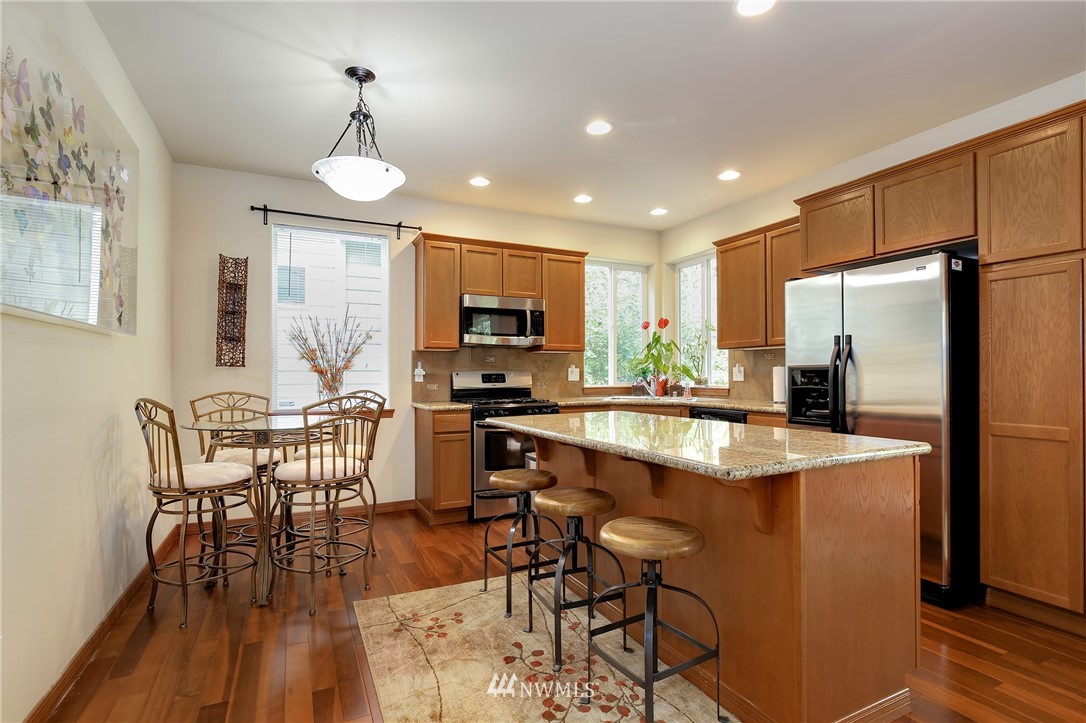 17801 20th Avenue Southeast Bothell, WA 98012 - Photo 6 of 25 a kitchen with stainless steel appliances granite countertop a stove refrigerator a dining table and chairs with wooden floor