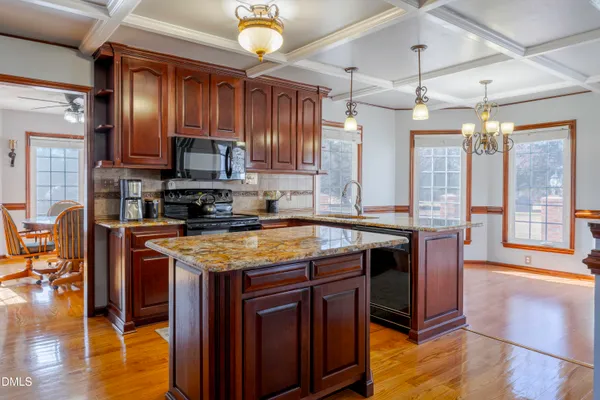 a kitchen with stainless steel appliances granite countertop wooden cabinets a stove a sink and a counter space