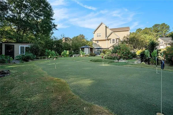 a backyard of a house with table and chairs plants and large tree