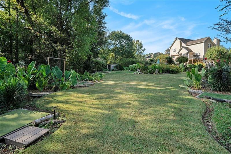 5303 Meadows Lake Crossing Southwest Powder Springs, GA 30127 - Photo 46 of 53 a backyard of a house with table and chairs plants and large tree