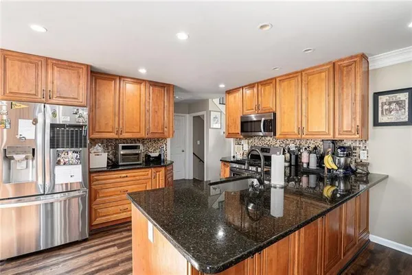 a kitchen with stainless steel appliances granite countertop a sink a stove and a wooden cabinets