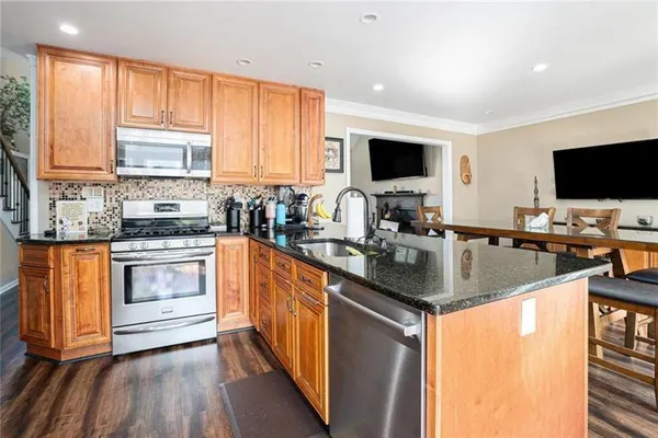 a kitchen with stainless steel appliances a stove top oven a sink a counter space and a window