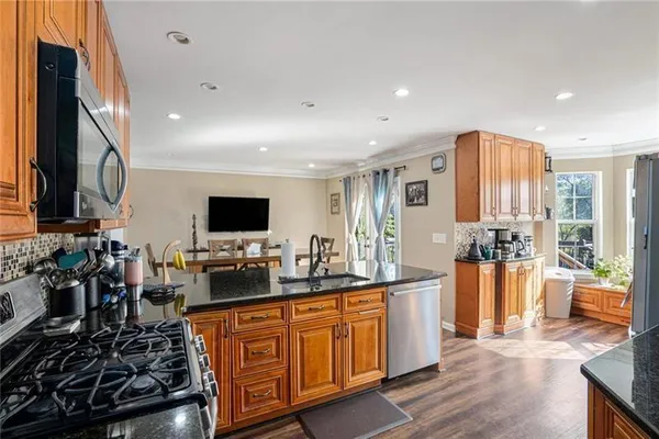 a large kitchen with stainless steel appliances a large counter top a stove a chimney a sink and a refrigerator