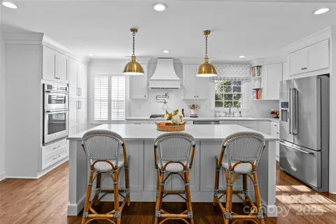 a kitchen with stainless steel appliances a dining table chairs sink refrigerator and microwave