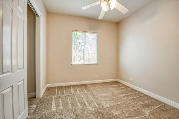 an empty room with a chandelier fan and windows