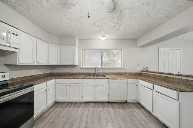 a kitchen with granite countertop white cabinets and white appliances
