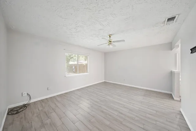 a view of an empty room with a window and wooden floor