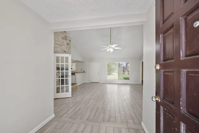 an empty room with wooden floor cabinet and windows