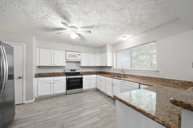 a large kitchen with cabinets wooden floor and stainless steel appliances